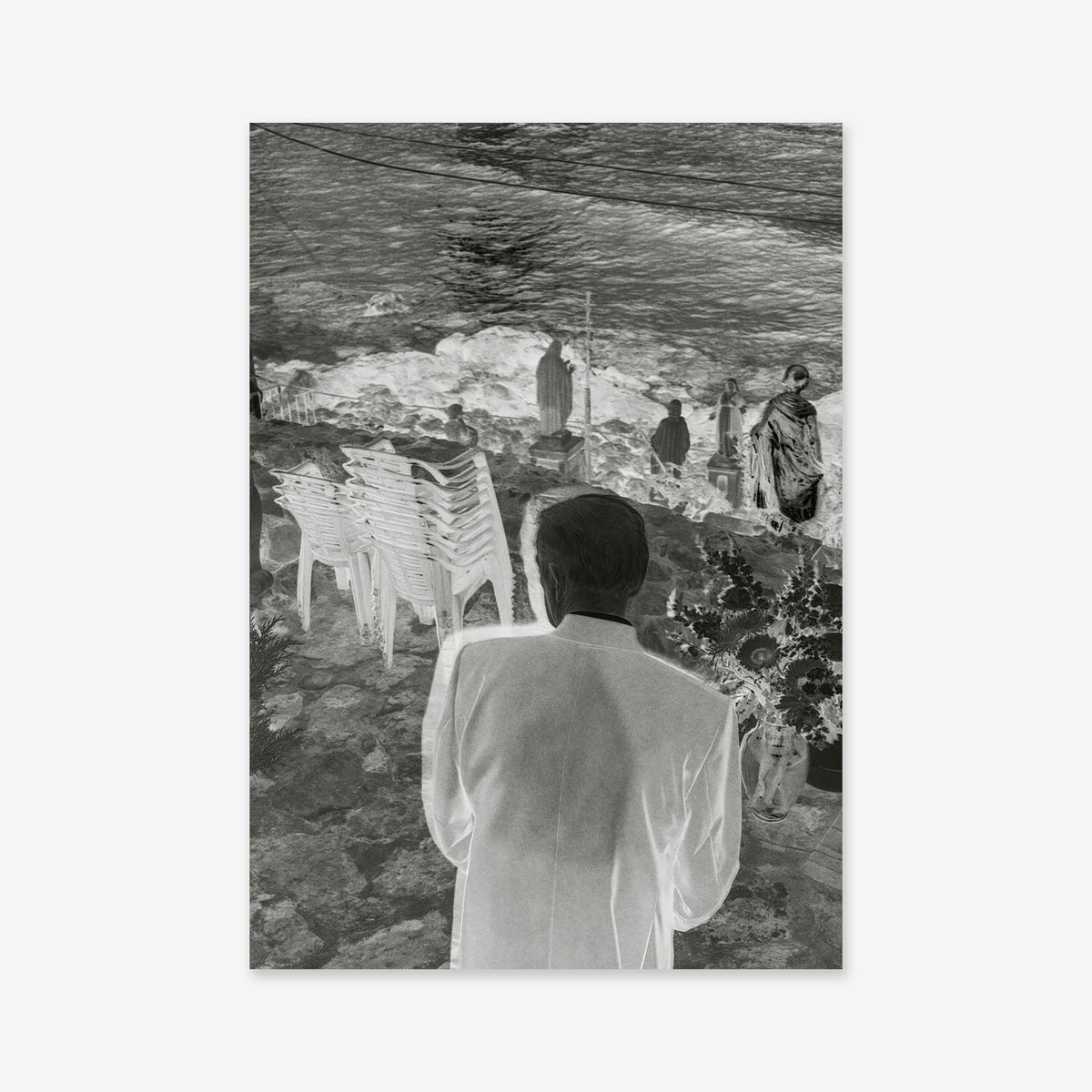 The Dies rae Giclée art print shows a man in a light-colored suit standing on a stone patio overlooking the sea, with statues lining a nearby wall and a stack of chairs resting against the ledge.